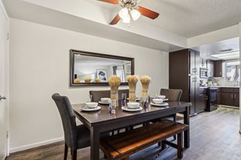 A dining room with a table set for two and a bench.